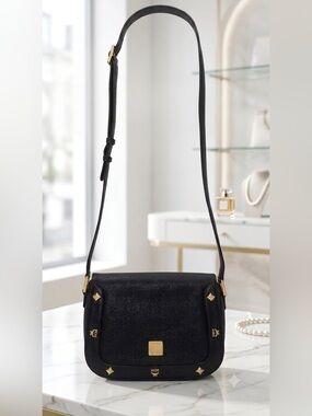 MCM crossbody bag featuring gold-tone hardware and stud embellishments.
